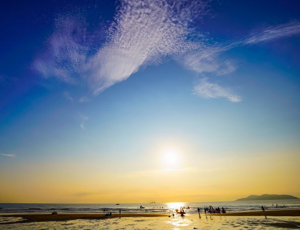 Morning on the beach of Cua Lo, Nghe An, Vietnam. People are walking, swinming and playing while the fishermen are coming home after working through the night. There is also a very nice-shaped cloud.; Shutterstock ID 1485546101; purchase_order: -; job: -; client: -; other: -